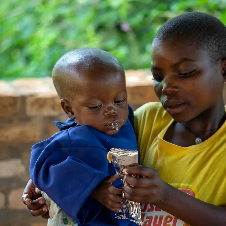 Die 12-jährige Evelyne füttert ihren mangelernährten Bruder mit Erdnusspaste | © UNICEF/Prinsloo Burundi Mangelernährung: Ein Mädchen füttert seinen kleinen mangelernährten Bruder mit Erdnusspaste