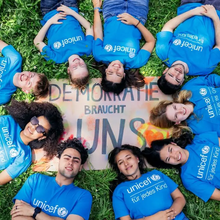 Ehrenamtliche liegen in einem Kreis um ein Plakat herum.