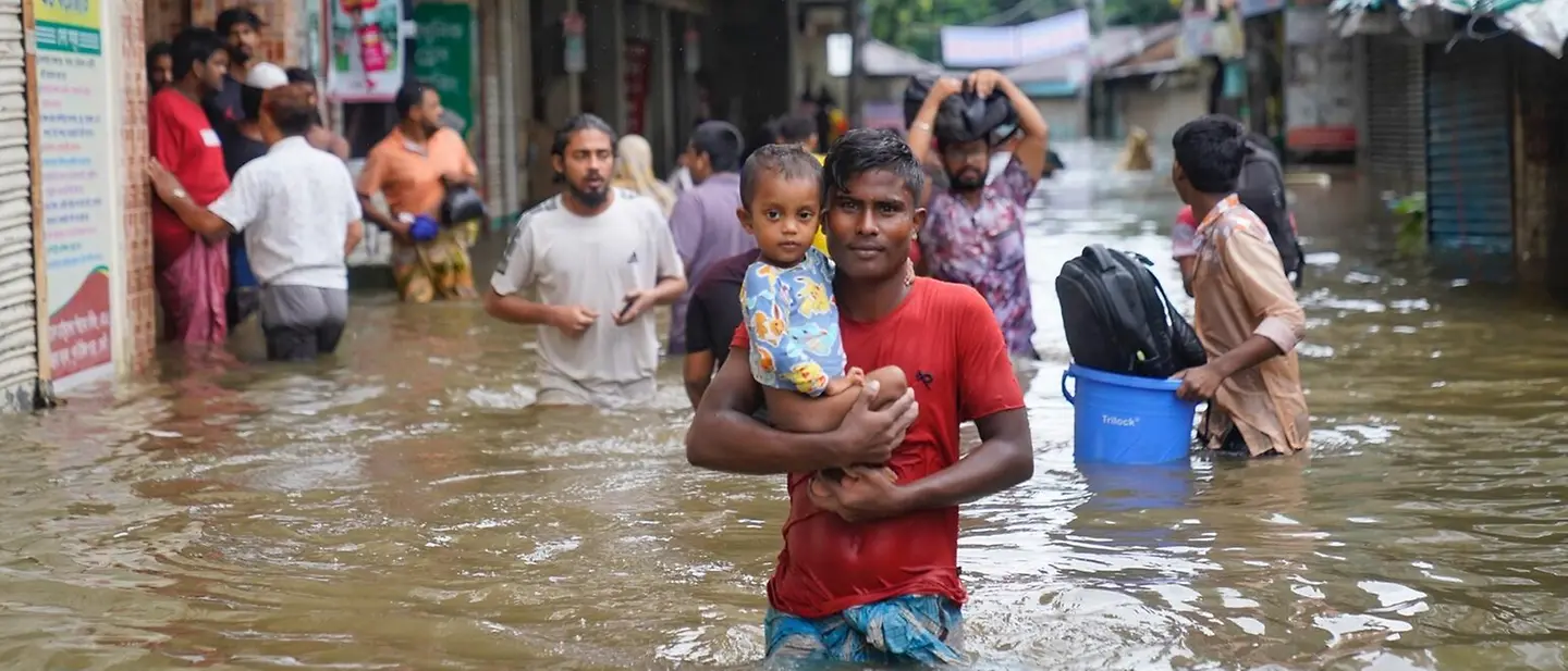 Naturkatastrophen spenden: Ein Vater trägt sein Kind durch überschwemmte Straßen. | © UNICEF/Mukut Naturkatastrophen spenden: Ein Vater trägt sein Kind durch überschwemmte Straßen.
