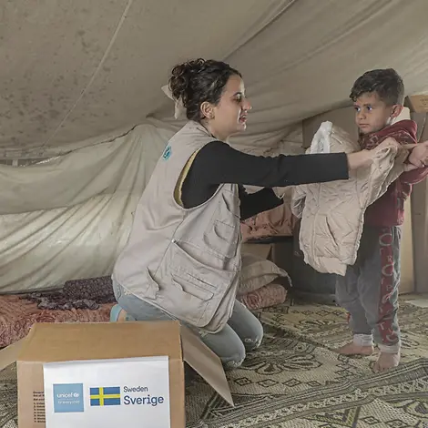 Eine UNICEF-Mitarbeiterin verteilt Winterkleidung an eine Familie in Gaza | UNICEF/Nateel Gaza Hilfsgüter: Verteilung von Winterkleidung