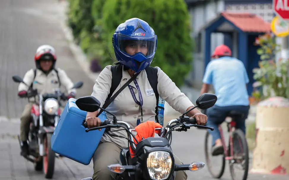 Glenda fährt mit ihrem Kollegen zur nächsten Impfung. | © UNICEF/Leiva El Salvador: Glenda fährt mit ihrer Kühlbox voller Impfungen Motorad.