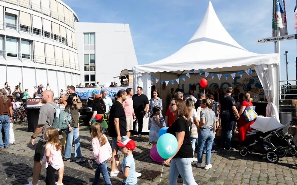 Weltkindertag: Kinder und Erwachsene stehen vor einem Zelt von UNICEF auf dem Festival. 