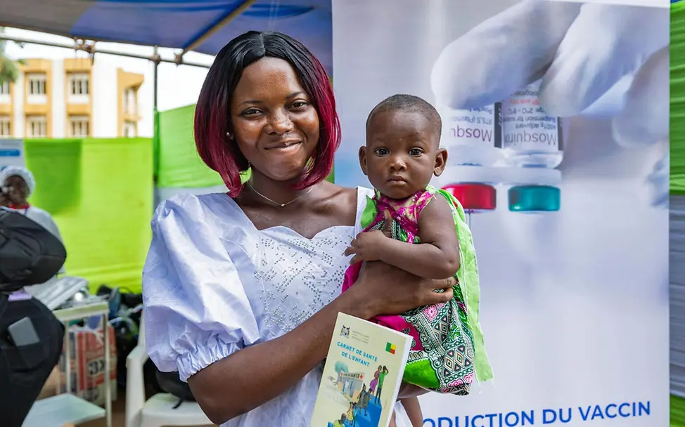 Malaria Kinder schützen: Eine lächelnde Mutter mit ihrem Baby auf dem Arm, das eben gegen Malaria geimpft wurde. 