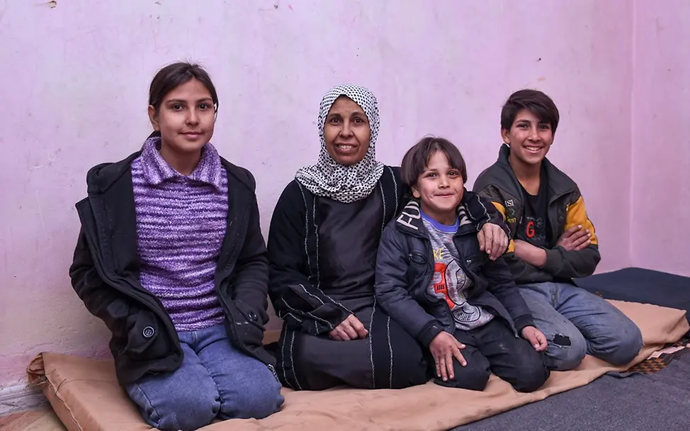Farha sitzt mit ihren Kindern in ihrer kleinen Wohnung.