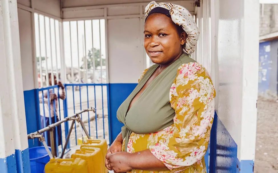 Demokratische Republik Kongo Nothilfe: Eine Frau hilft an einer Wasserstelle Familien beim Abfüllen von sauberem Wasser 