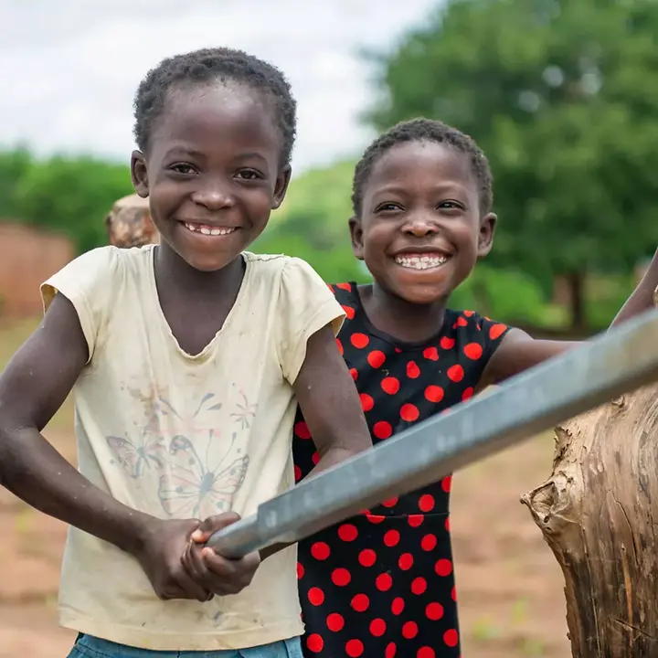 Sambia Wasser und Hygiene: Zwei Mädchen pumpen lächelnd Wasser 