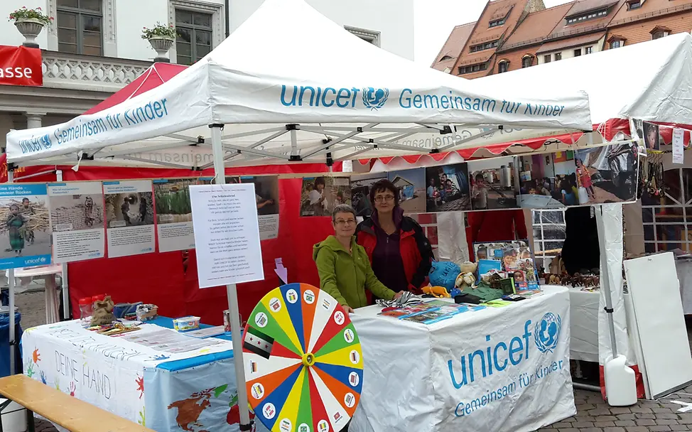 Unser Stand mit Schicksalsrad beim Markt der Kulturen Ehrenamtliche von UNCICEF informieren am Stand mit dem Schicksalsrad (Glücksrad mit Länderflaggen)