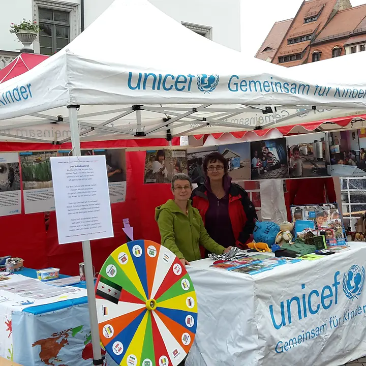 Unser Stand mit Schicksalsrad beim Markt der Kulturen Ehrenamtliche von UNCICEF informieren am Stand mit dem Schicksalsrad (Glücksrad mit Länderflaggen)