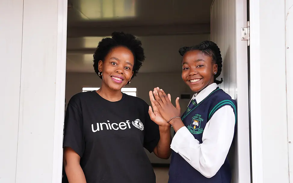 Eine Schülerin mit einer UNICEF-Mitarbeiterin für digitale Medien an einer weiterführenden Schule in Südafrika | © UNICEF/Mkhize Mädchenbildung in Südafrika: Die UNICEF-Bildungsprogramme fördern speziell die Chancen von Mädchen