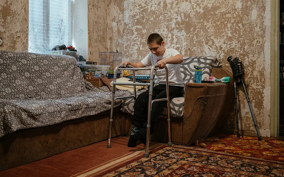 Ukraine Teenager: Nazar steht mit Hilfe seiner Gehhilfe langsam auf