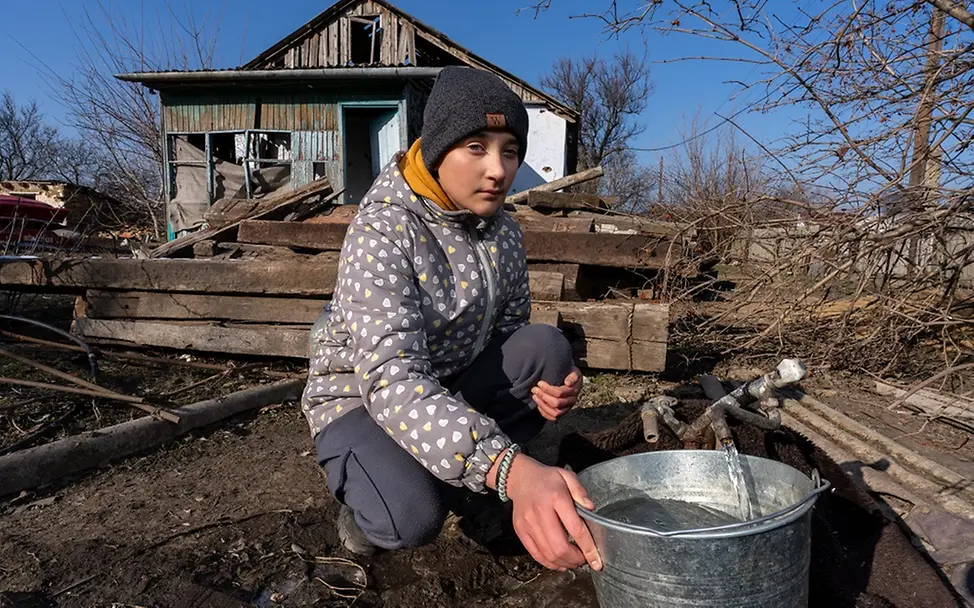 Ukraine Teenager: Yana (14) holt mit einem Eimer Wasser aus einem Brunnen