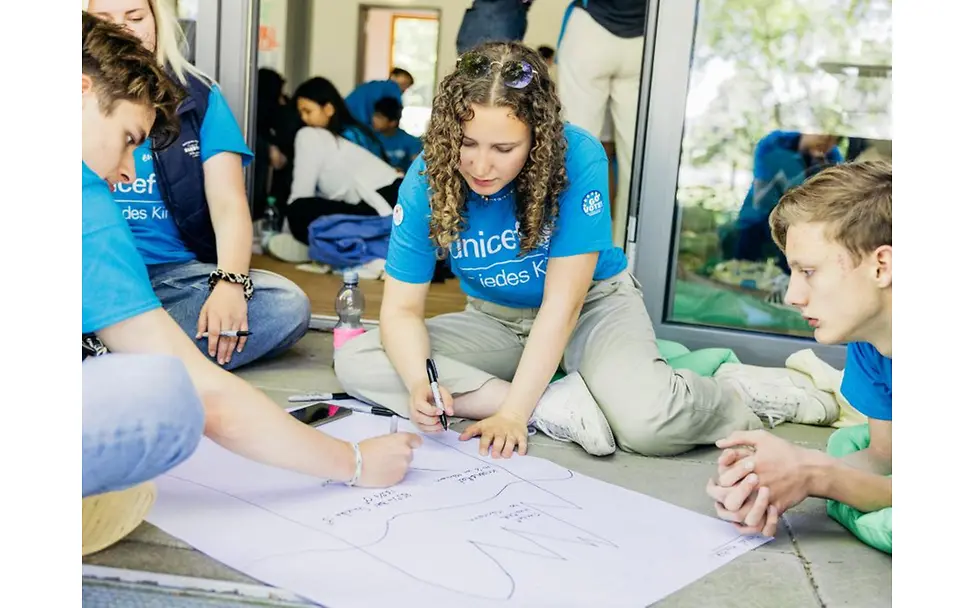 Teilnehmende des Youth Festival gestalten ein Poster gemeinsam.
