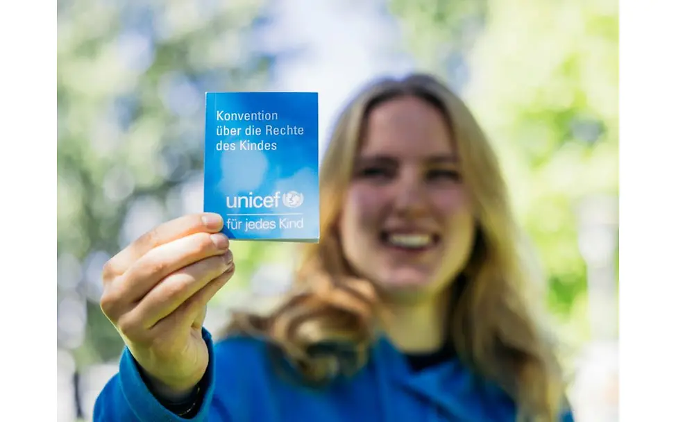 Teilnehmerin zeigt UNICEF Flyer.