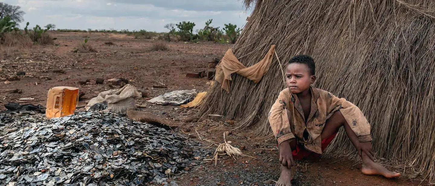 Der 8-jährige Tsifeheza sitzt neben dem Eingang zur Glimmermine auf dem Boden und schaut in die Ferne. 