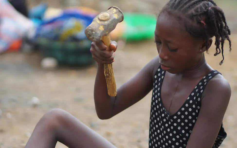 Die 12-jährige Adama bei der Arbeit mit einem Hammer in der Hand.