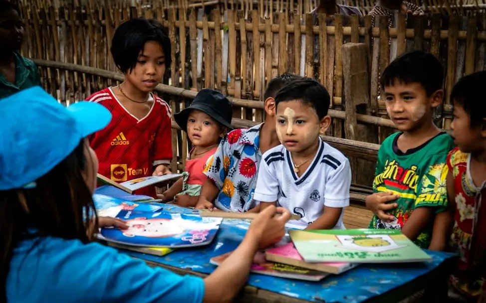 UNICEF-Mitarbeiterin liest Kindern in Myanmar nach einem Erdbeben Geschichten vor.