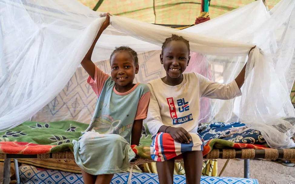 Zwei Kinder im Sudan sitzen unter einem Moskitonetz | © UNICEF/Rajab Spenden Sudan Nothilfe: Zwei aus Khartum geflohene Geschwister sitzen unter einem Moskitonetz.
