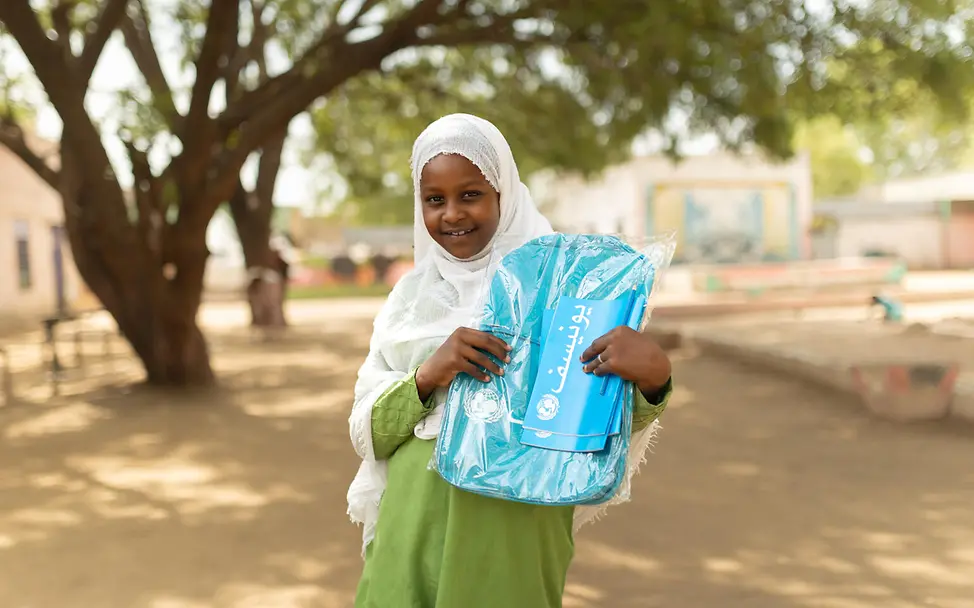 Ein aus Khartum geflüchtetes Mädchen zeigt ihren UNICEF-Schulrucksack | © UNICEF/Dawod Spenden Sudan Nothilfe: Ein aus Khartum geflüchtetes Mädchen hält ihren UNICEF-Schulrucksack hoch