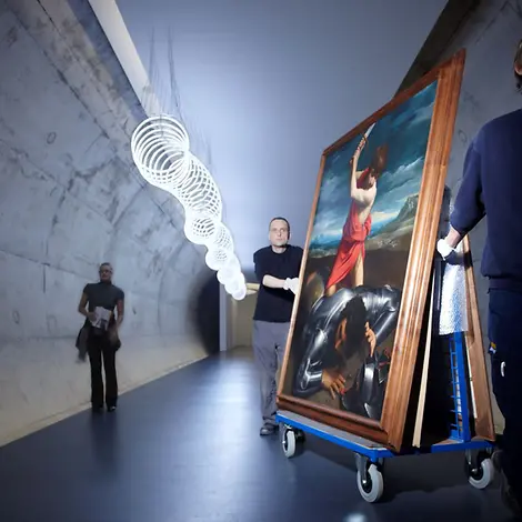 Sammlung Rau: Mensch transportiert ein Gemälde auf einem Rollwagen durch einen schmalen Gang.