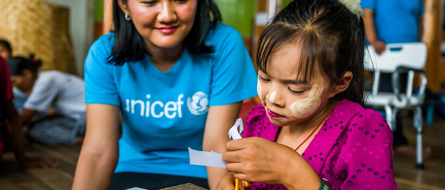 Eine UNICEF-Helferin beobachtet ein Mädchen in einem Lernzentrum für Kinder mit Behinderung beim Basteln | © UNICEF/Oo Myanmar spenden: Eine UNICEF-Helferin beobachtet ein Mädchen in einem Lernzentrum beim Basteln