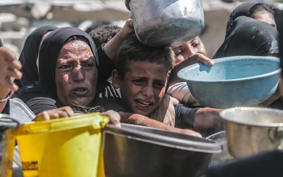 Kinder versuchen, bei einer Essensausgabe in Gaza an Lebensmittel zu gelangen.