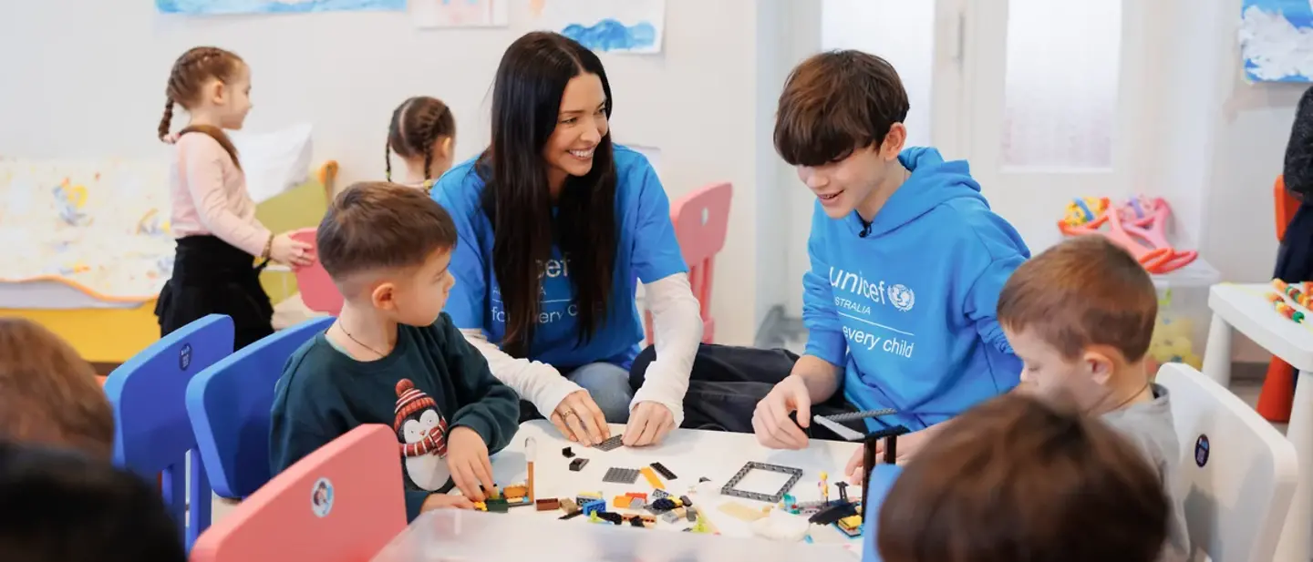©UNICEF Australia A mother and her teenage son sitting in a colourful room playing with children_