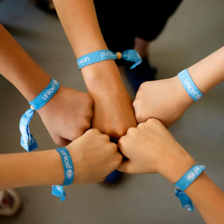 Kinderhände mit einem UNICEF-Bändchen.