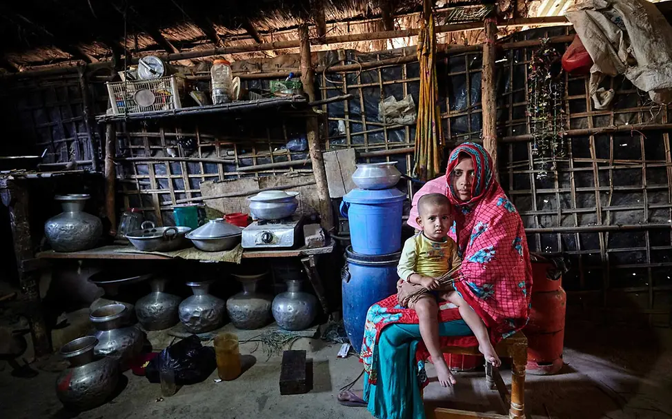 Kinderarmut: Eine alleinerziehende Mutter in Bangladesch hält in ihrer Küche ihr Kind auf dem Schoß. 