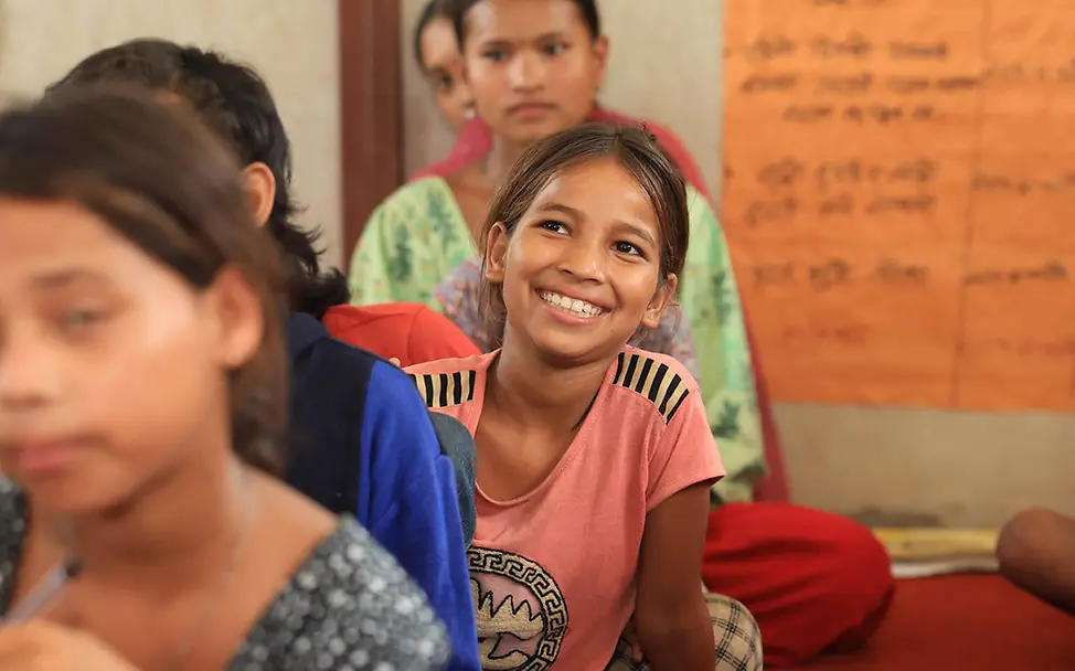 Kinderarmut spenden: Ein Mädchen in Nepal sitzt lächelnd in einem von UNICEF aufgebauten Kinderzentrum. 