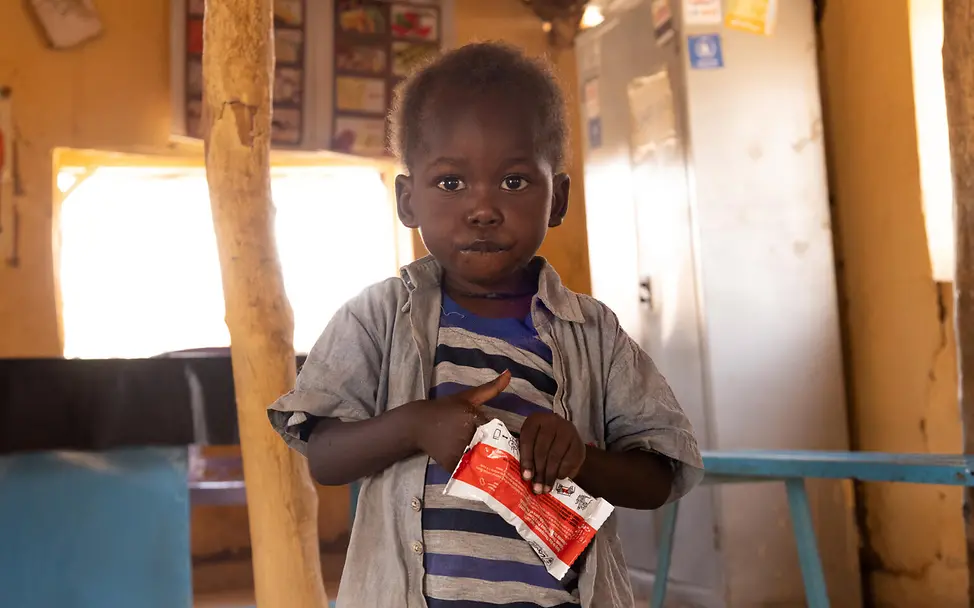 Ein kleiner Junge im Sudan isst einen nährstoffreichen Riegel. I © UNICEF/UNI825281/Elfatih Im Sudan sind Millionen Kinder unterernährt. UNICEF hilft mit Hilfsgütern wie therapeutischer Kraftnahrung.