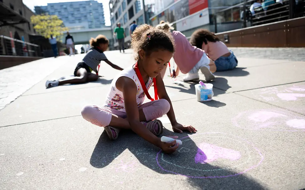 Weltkindertag 2024: Kinder malen mit Kreide auf dem Boden