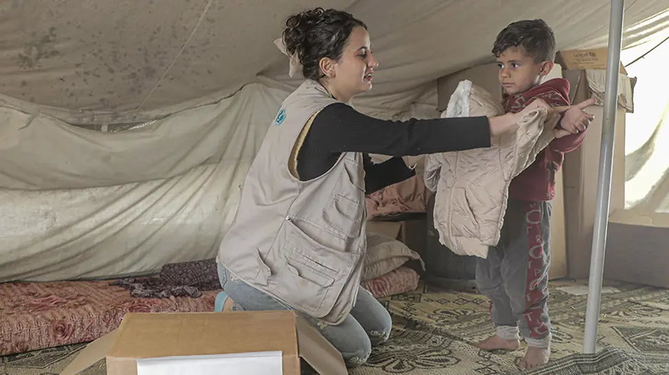 Gaza: UNICEF Helferin überreicht Kind Winterkleidung. | © UNICEF/Nateel Gaza: UNICEF Helferin überreicht Kind Winterkleidung.