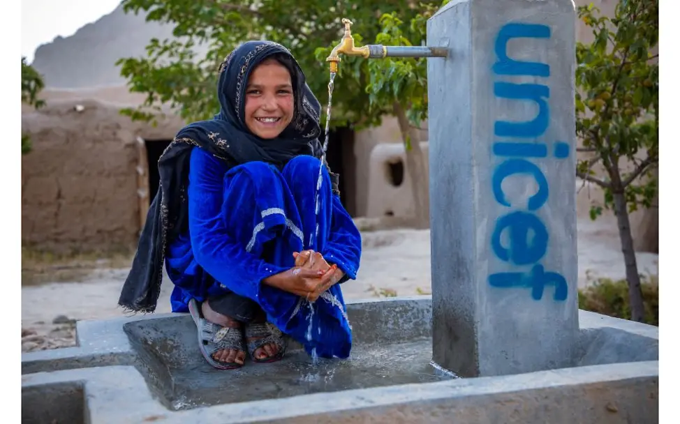 Afghanistan: Mädchen sitzt an Brunnen.