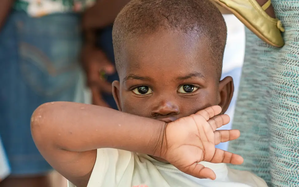 Ein Kind blickt in die Kamera, während es in einer von UNICEF unterstützten mobilen Klinik in Boucan Carré (Haiti) wartet. | © UNICEF/Joseph UNI792737