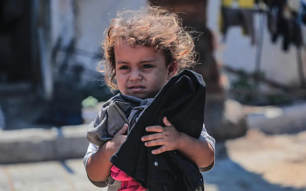 Gaza spenden Waffenruhe: Ein Kleinkind in einem Flüchtlingscamp hält Kleidung im Arm. 