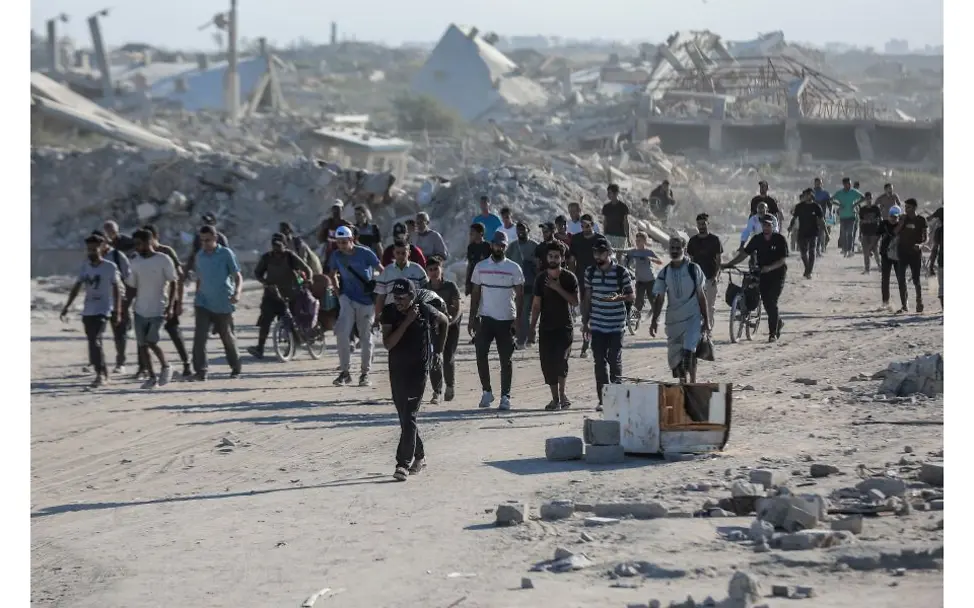 Menschen aus Gaza laufen durch zerstörtes Gebiet.