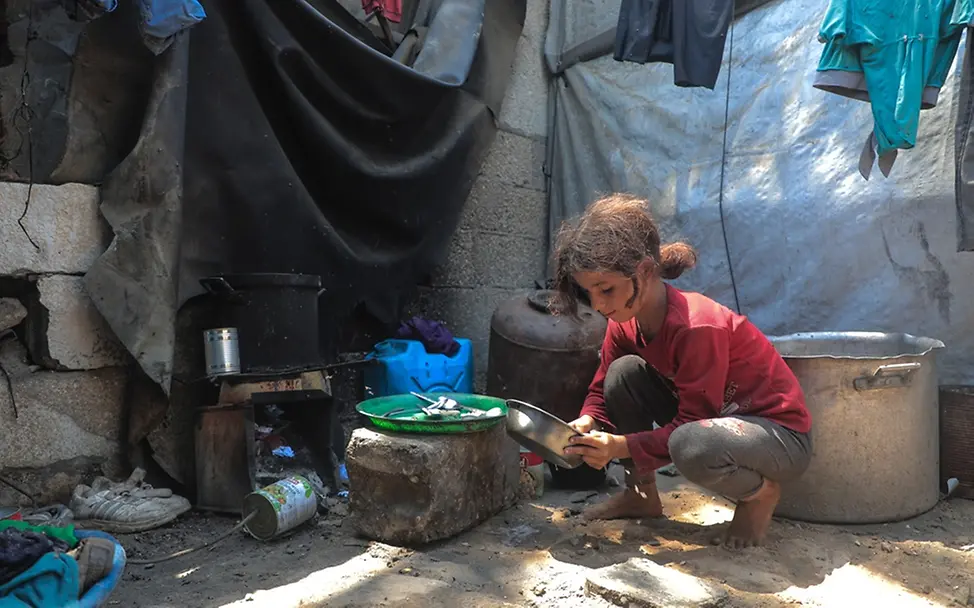 Tala (10) in einer Notunterkunft | UNICEF/Nateel Kinder in Gaza: Ein Mädchen sitzt an einer Kochstelle in einer Notunterkunft