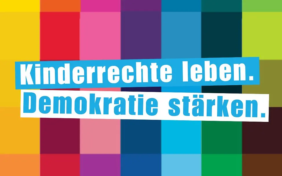 Kinderrechte leben, Demokratie stärken. Vor farbigen Kacheln steht in blau der Text "Kinderrechte leben, Demokratie stärken."