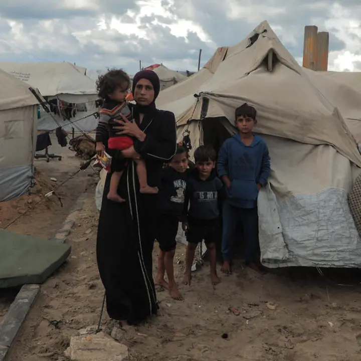 Maysaa lebt mit ihren Kindern in einem Zelt | UNICEF/Nateel Maysaa steht mit ihren Kindern vor einem provisorischen Zelt