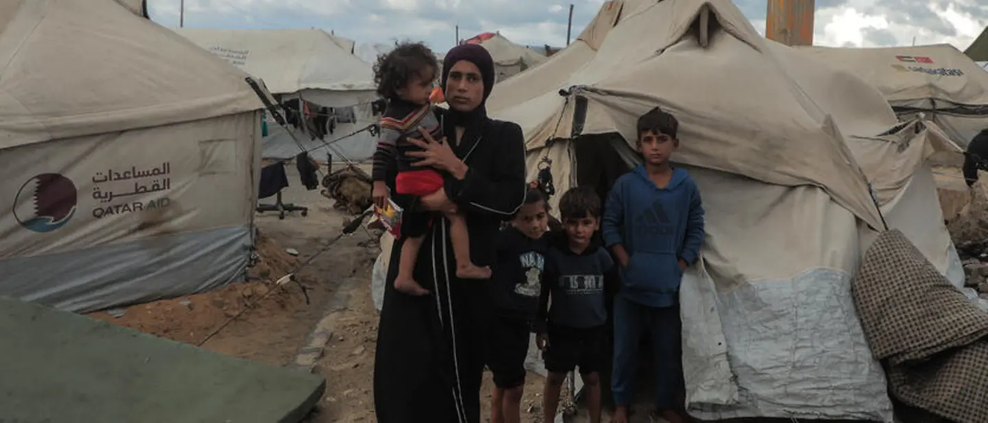 Maysaa steht mit ihren Kindern vor einem provisorischen Zelt
