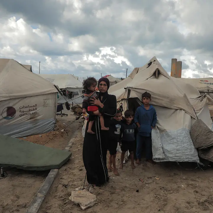 Maysaa steht mit ihren Kindern vor einem provisorischen Zelt