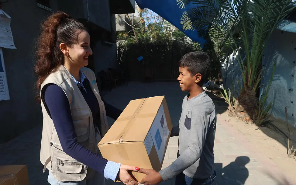 Spenden zu Weihnachten: Eine UNICEF-Helferin übergibt einem Jungen in Gaza ein Paket.