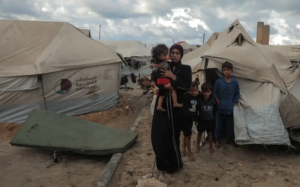 Spenden zu Weihnachten: Eine Mutter steht mit ihren Kindern vor einem Zelt in einem Flüchtlingscamp.