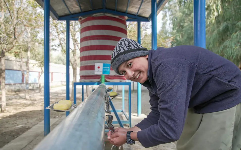 Originelle Geschenkideen für einen guten Zweck: Ein Junge trinkt Wasser aus einer Wasserleitung im Freien. 