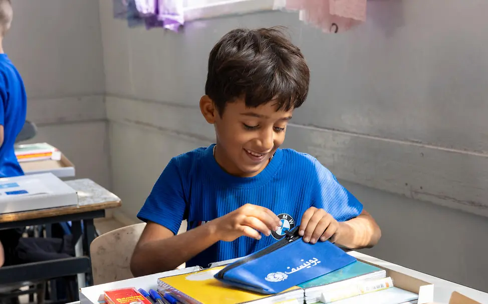Originelle Geschenkideen für einen guten Zweck: Ein Schüler schaut sich im Klassenraum seine neuen Schulmaterialien an. 