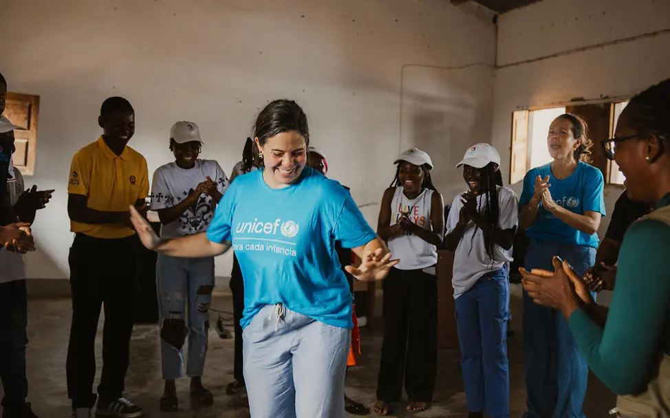 Originelle Geschenkideen für einen guten Zweck: Eine UNICEF-Helferin tanzt mit Jugendlichen in Mosambik. 