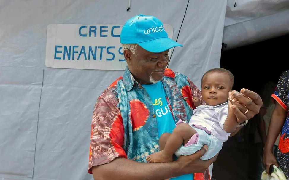 Ebola Kongo: Ein UNICEF-Kinderschutz-Mitarbeiter hält ein Baby in einer von UNICEF eingerichteten Kinderkrippe auf dem Arm. 