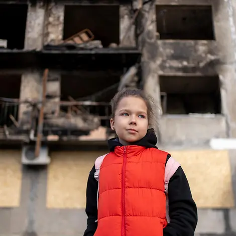 Mit Kindern über Krieg sprechen: Altersgerecht Ängste nehmen. Mit Kindern über Krieg sprechen: Ein Mädchen vor den Trümmern eines Hauses im ukrainischen Kiew.