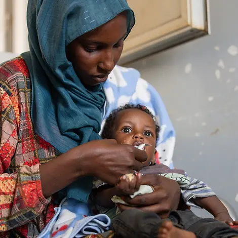 Adnan aus dem Sudan wird mit Erdnusspaste gefüttert | UNICEF/Elfatih Hunger im Sudan: Naba füttert ihren Sohn Adnan mit Erdnusspaste