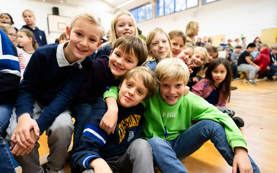 Kinderrechte leicht erklärt: Eine Gruppe Kinder posiert in einer Schulsporthalle.